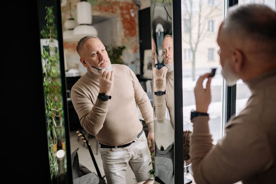 Middle-aged man applying beard care, examining reflection indoors, embracing modern grooming.
