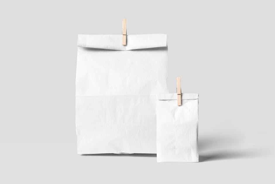Two white paper bags with clothes pins on a plain background, ideal for mockups and design presentations.