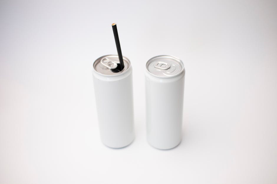 Close-up of two white cans, one with a straw, on a plain background, highlighting minimalism.