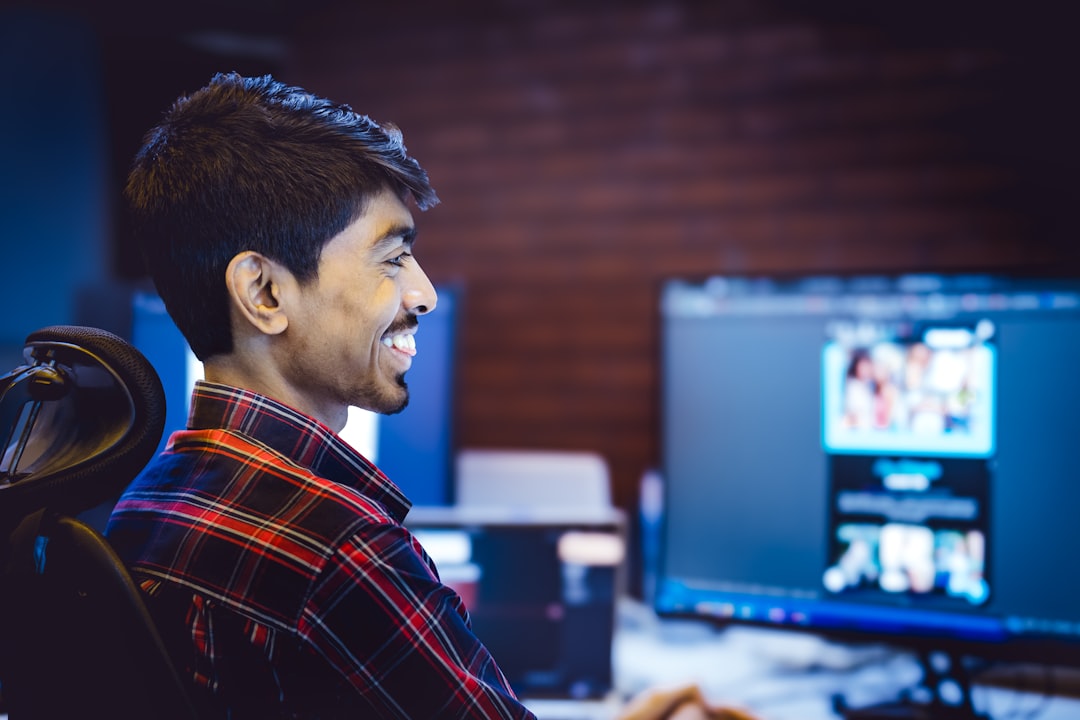 A man smiles while working on a computer.