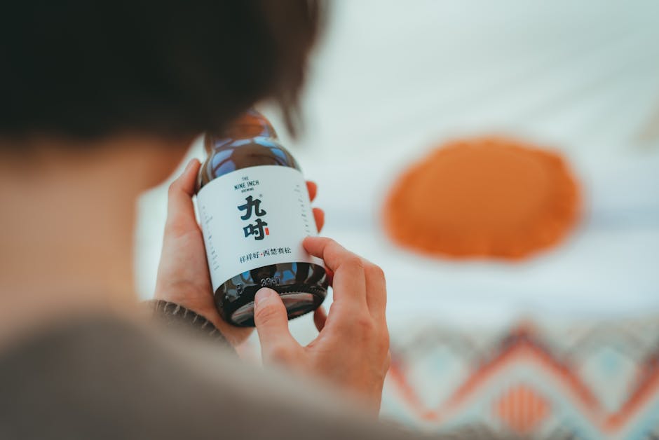 Close-up of a person holding a bottle labeled with Asian calligraphy.