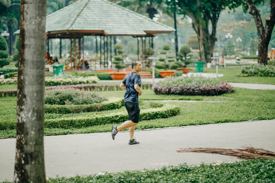 a man running in a park with a gazebo in the background