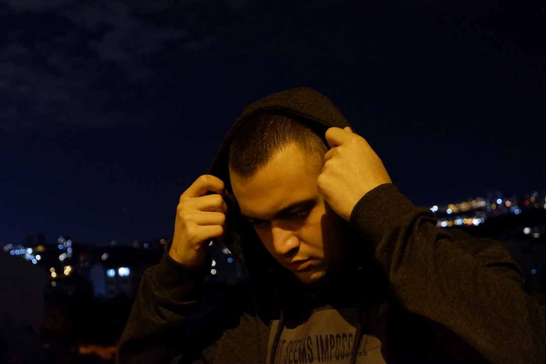 man in black hoodie holding his face