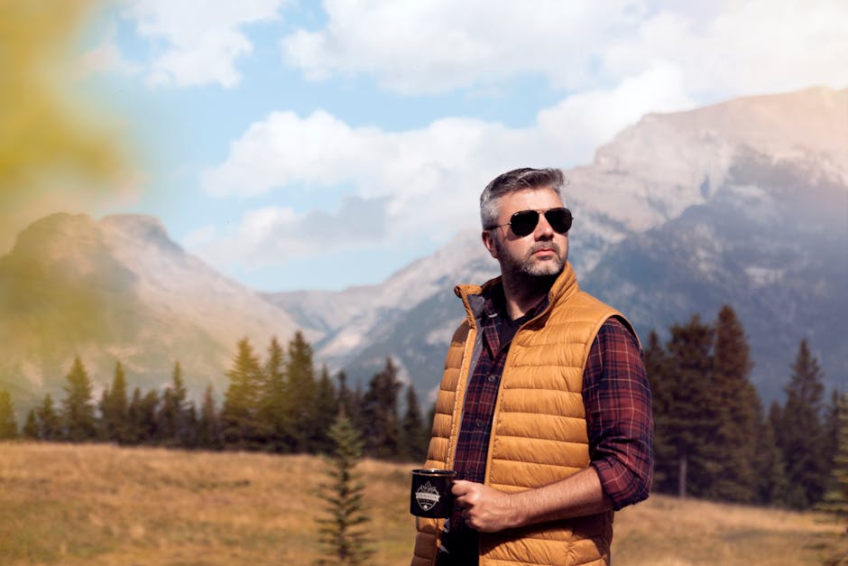 Man in vest with coffee mug looking at mountains in Canmore, Alberta.
